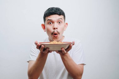 Neşeli genç bir adam bir kase yemek uzatıyor, keyifli olduğunu söylüyor..