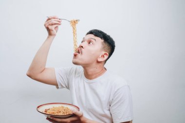 Bir adam bir kase hazır erişteden zevk alır, her lokmayı neşeyle yer..