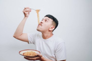 Bir kase eriştenin tadını çıkaran bir adam basit bir ortamda neşe sergiliyor..