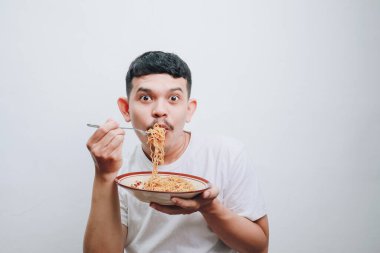 Genç bir adam lezzetli eriştesinin tadını basit bir ortamda şevkle çıkartır..