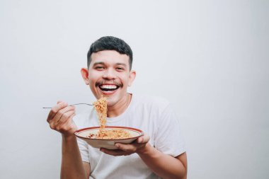 Neşeli genç bir adam mutlu mesut hazır erişte yiyor..