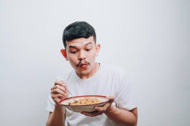 Bir kase eriştenin keyfini çıkaran genç bir adam heyecan ve beklenti iletiyor..