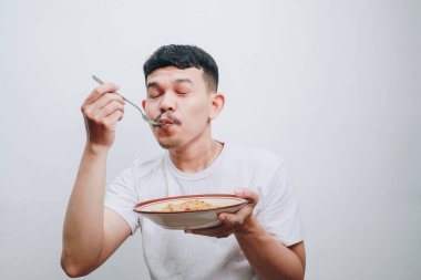 Neşeli bir adam, bir kase eriştenin tadını çıkararak, konforlu yemeğin özünü yakalar..