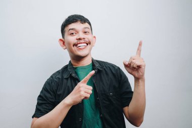 Neşeli genç bir adam heyecanlı bir şekilde arka planı işaret ediyor..