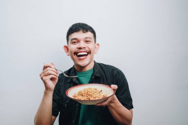 Neşeli bir adam bir kase eriştenin keyfini çıkarıyor, mutluluğu ve aşçılık neşesini somutlaştırıyor..