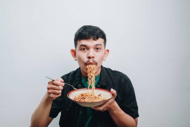 Genç bir adam buharda pişmiş ramen yemekten zevk alır..