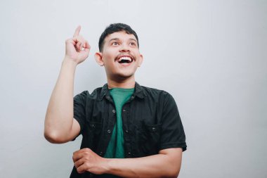 Neşeli genç bir adam bir gülümsemeyle heyecan ifade ediyor ve parmağını kaldırıyor..
