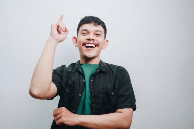 Neşeli genç bir adam yukarıya doğru işaret ederken heyecanını ifade eder..