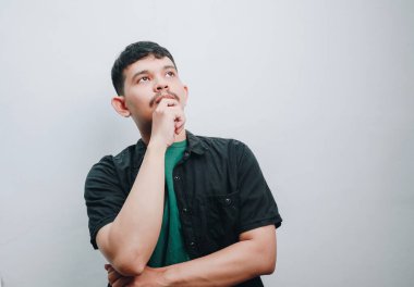 Genç bir adam düşünceli ve düşünceli görünüyor, derin düşüncelere dalmış..