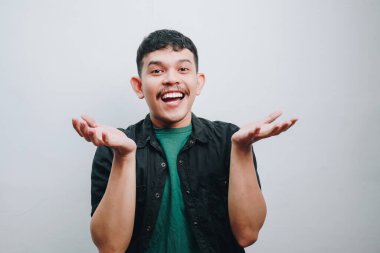 Mutlu bir genç adam geniş ellerle gülümser, neşe saçar ve pozitiftir..