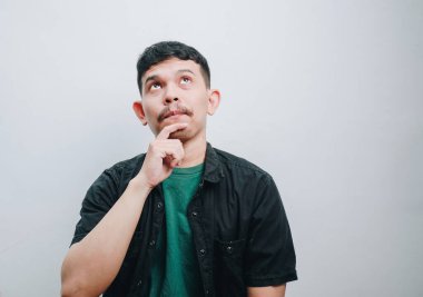 Siyah gömlekli düşünceli bir adam minimalist bir ortamda fikirlerini düşünüyor..