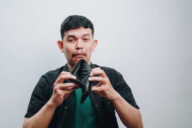 Bir adam elinde boş bir cüzdan tutarken hayal kırıklığı yaşar, finansal zorlukları simgeler..