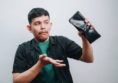 Bir adam ümitsiz görünüyor, boş cüzdanına bakıyor, mali hayal kırıklığını ifade ediyor..