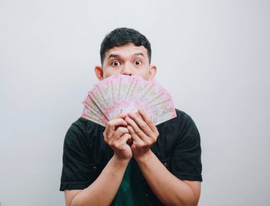 Genç bir adam, yüzüne para tutarken heyecanlı görünür..