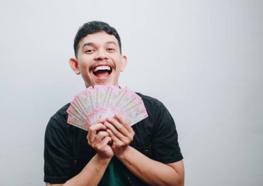 Genç bir adam mutlulukla ve heyecanla parasıyla neşe içinde sergiliyor..