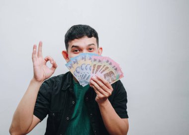 Stüdyoda neşeli bir şekilde para gösteren genç bir adam..