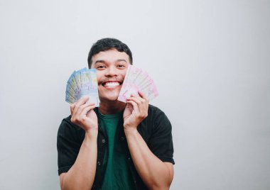 Genç bir adam neşeli bir gülümsemeyle renkli paralar sergiliyor..