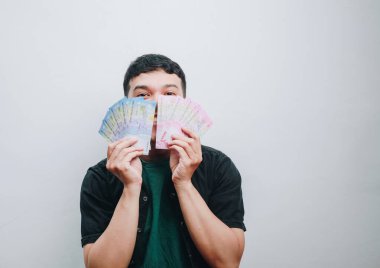 Yüzünün önünde renkli banknotlar tutan neşeli bir insan..