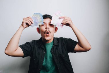 Elinde nakit parayla sevinç ifade eden genç bir adam, heyecanı ve kutlamaları somutlaştırıyor.