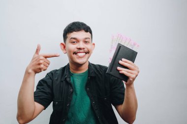 Nakit para ve defter gösteren neşeli genç bir adam. Mutluluk ve kendine güveni somutlaştıran..