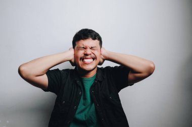 Genç bir adam büyük bir gülümsemeyle kulaklarını kapatırken mutluluk ve neşe gösterir..