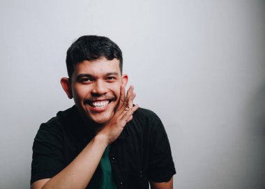 Siyah gömlekli neşeli bir adam şakacı bir poz verir, mutluluğu ve sıcaklığı gösterir..