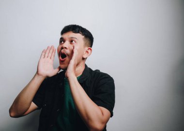 Neşeli bir genç adam neşeli hareketlerle şaşkınlık ve coşku ifade ediyor..