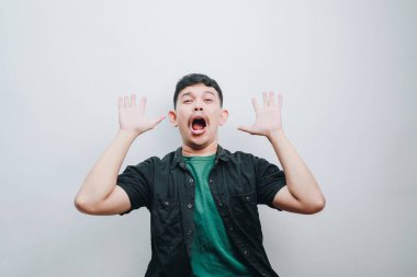 Genç bir adam minimalist bir ortamda şaşkınlık ve heyecan gösterir..