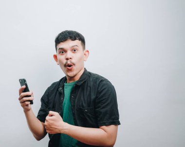 Elinde akıllı bir telefon tutan, neşe ve heyecanı ifade eden şaşırmış genç bir adam..