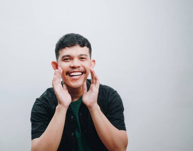 Geniş bir gülümseme ve açık ellerle mutluluğu ifade eden neşeli genç bir adam..