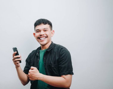 Telefonu olan neşeli bir adam, sade bir arka planda mutluluğu ifade ediyor..