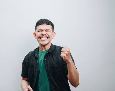 Genç bir adam neşe ve kararlılık saçar geniş bir gülümsemeyle ve yumruğunu kaldırarak..