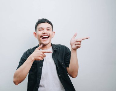 Neşeli genç bir adam poz verir, minimalist bir ortamda parlayarak ve gülümseyerek.