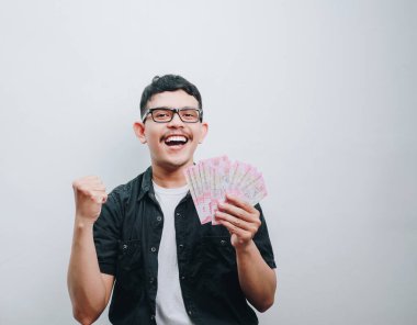 Neşeli genç bir adam para tutar, heyecan ve zafer ifade eder..