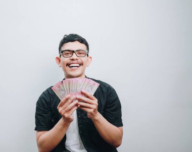 Neşeli genç bir adam elinde nakit parayla kutlama yapar, heyecanını gösterir..