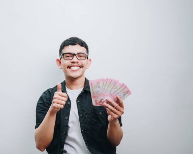 Neşeli genç bir adam, neşeli bir gülümsemeyle, neşe ve pozitiflikle nakit para gösteriyor..