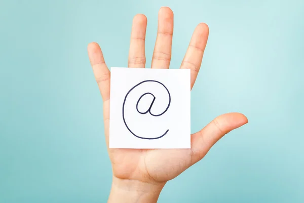 Hand mit Arroba-Symbol auf blauem Hintergrund — Stockfoto