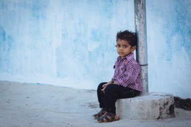 Maafushi, Maldivler - 5 Ocak 2013: Derin ciddi bir gözü mavi bir duvara yakın poz olan küçük Maldivlere çocuk