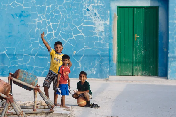 Maafushi, Maldivler - 5 Ocak 2013: Üç yalınayak Maldivlere çocuk renkli tişörtler fotoğrafçının dikkat çekiyor — Stok fotoğraf