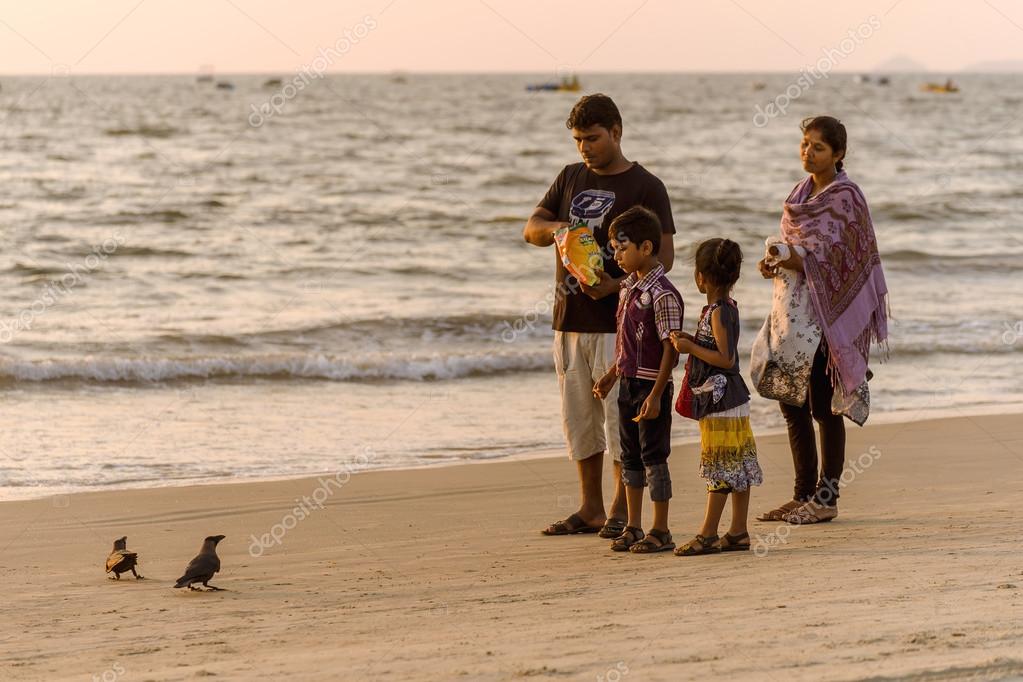 Indian family feeding birds at Goa beach Stock Editorial Photo