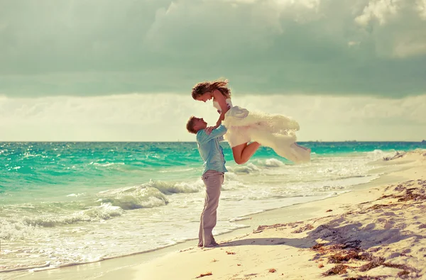 Bräutigam hält Braut am Strand in der Luft — Stockfoto