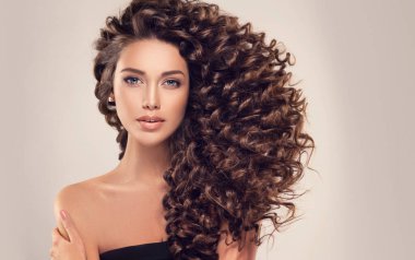 Uzun ve parlak kıvırcık saçlı esmer kız. Dalgalı saç stili olan güzel model kadın.