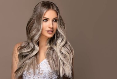 Güzel kızlar beyaz gelinlik içinde, saçları aşırı sarışınla boyanmış. Güzellik salonunda yapılan şık bukleler. Moda, kozmetik ve makyaj malzemeleri. Sevimli gelinler.
