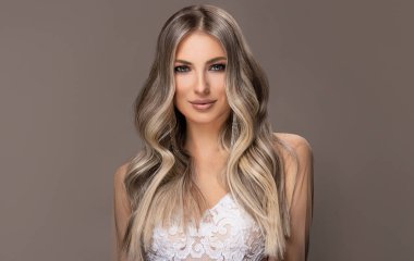 Güzel kızlar beyaz gelinlik içinde, saçları aşırı sarışınla boyanmış. Güzellik salonunda yapılan şık bukleler. Moda, kozmetik ve makyaj malzemeleri. Sevimli gelinler.