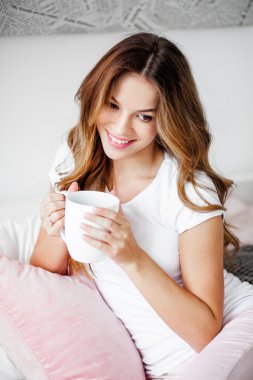 kadın büyük bir fincan çay ya da kahve tutuyor