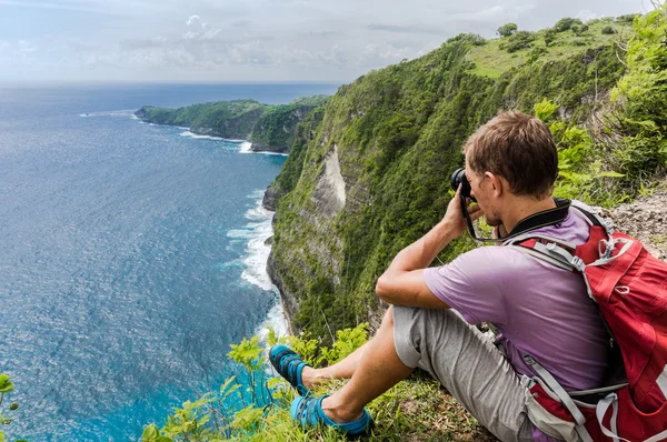 Tramp s batohem sedí na vrcholu hory a provedení Foto — Stock fotografie