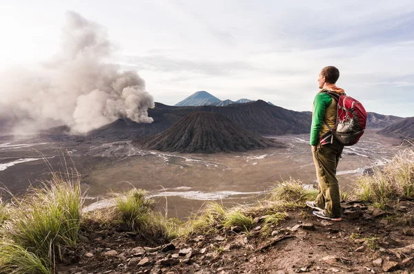 Man op de heuvel is op zoek op Bromo vulkaanuitbarsting. Oost-Java, Indonesië — Stockfoto