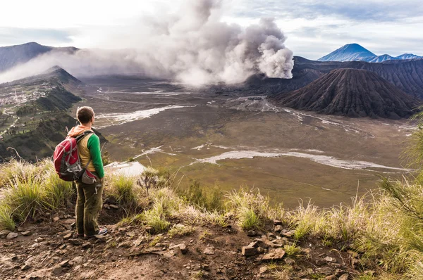 Man on the hill is looking on Bromo volcano eruption. East Java, Indonesia
