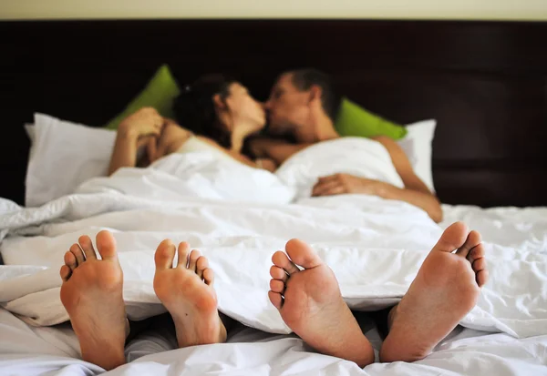 Bella coppia baciare a letto, concentrarsi sui piedi — Foto Stock