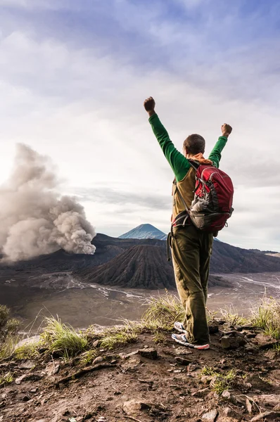 L'homme encouragé sur la colline regarde l'éruption du volcan Bromo Images De Stock Libres De Droits